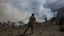 Seorang petugas pemadam kebakaran membawa selang saat memadamkan kebakaran hutan di Koycegiz, Mugla, Turki, Senin (9/8/2021). Kebakaran hutan di Turki telah menewaskan delapan orang serta hewan yang tidak terhitung jumlanya. (AP Photo/Emre Tazegul)