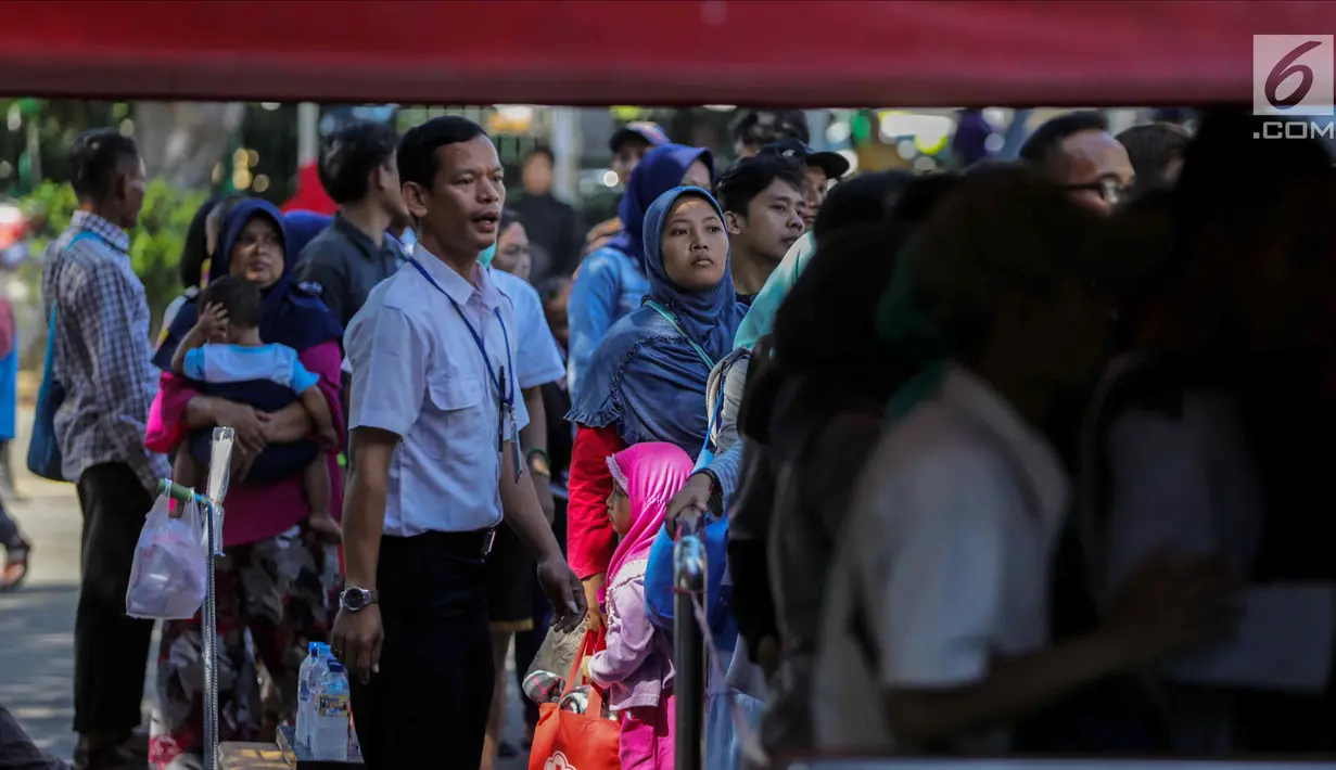 Petugas membantu warga untuk mengantre saat akan menaiki bus City Tour di kawasan Masjid Istiqlal, Jakarta, Senin (25/12). Mayoritas warga menggunakan moda transportasi massal ini menuju kawasan Kota Tua. (Liputan6.com/Faizal Fanani)