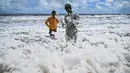 Anak-anak bermain di lapisan busa putih tebal yang beracun yang menutupi Pantai Marina yang tercemar di Chennai pada 22 Oktober 2025. (R. Satish BABU/AFP)