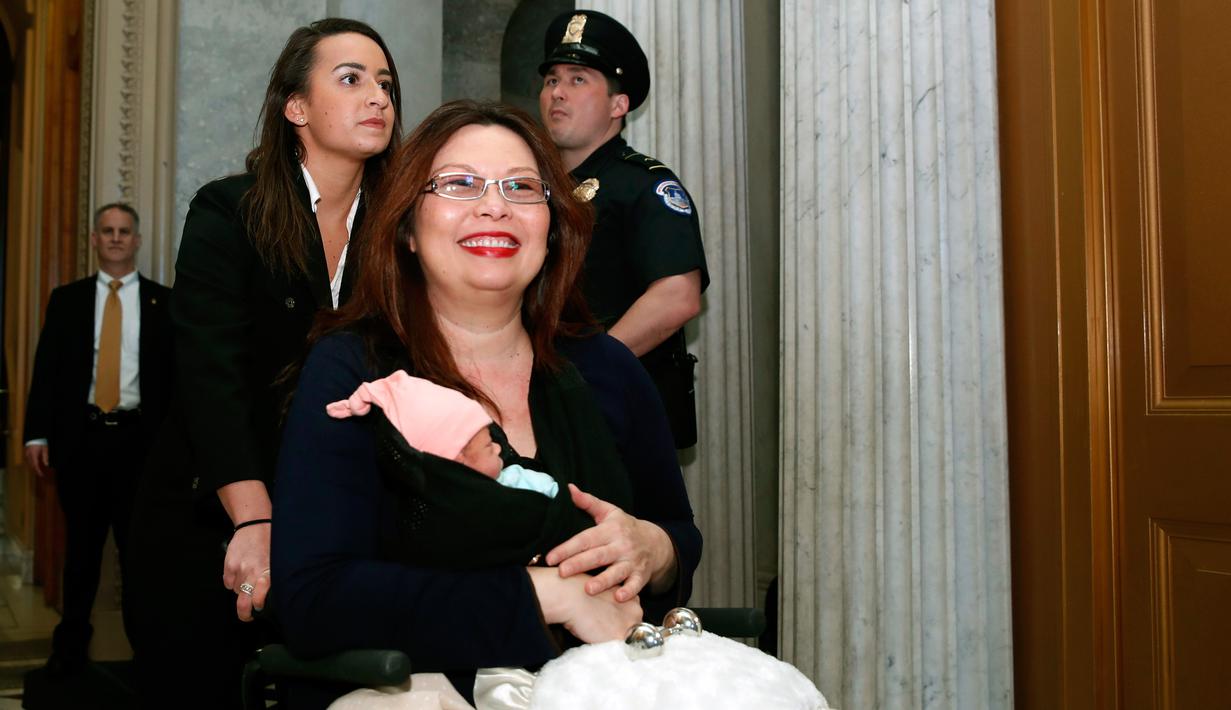 Senator Tammy Duckworth membawa bayinya meninggalkan ruang kongres Gedung Capitol Hill, Washington DC, Kamis (19/4). Amerika Serikat merupakan satu-satunya negara maju di dunia yang tidak menawarkan cuti kepada ibu yang melahirkan. (AP/Alex Brandon)