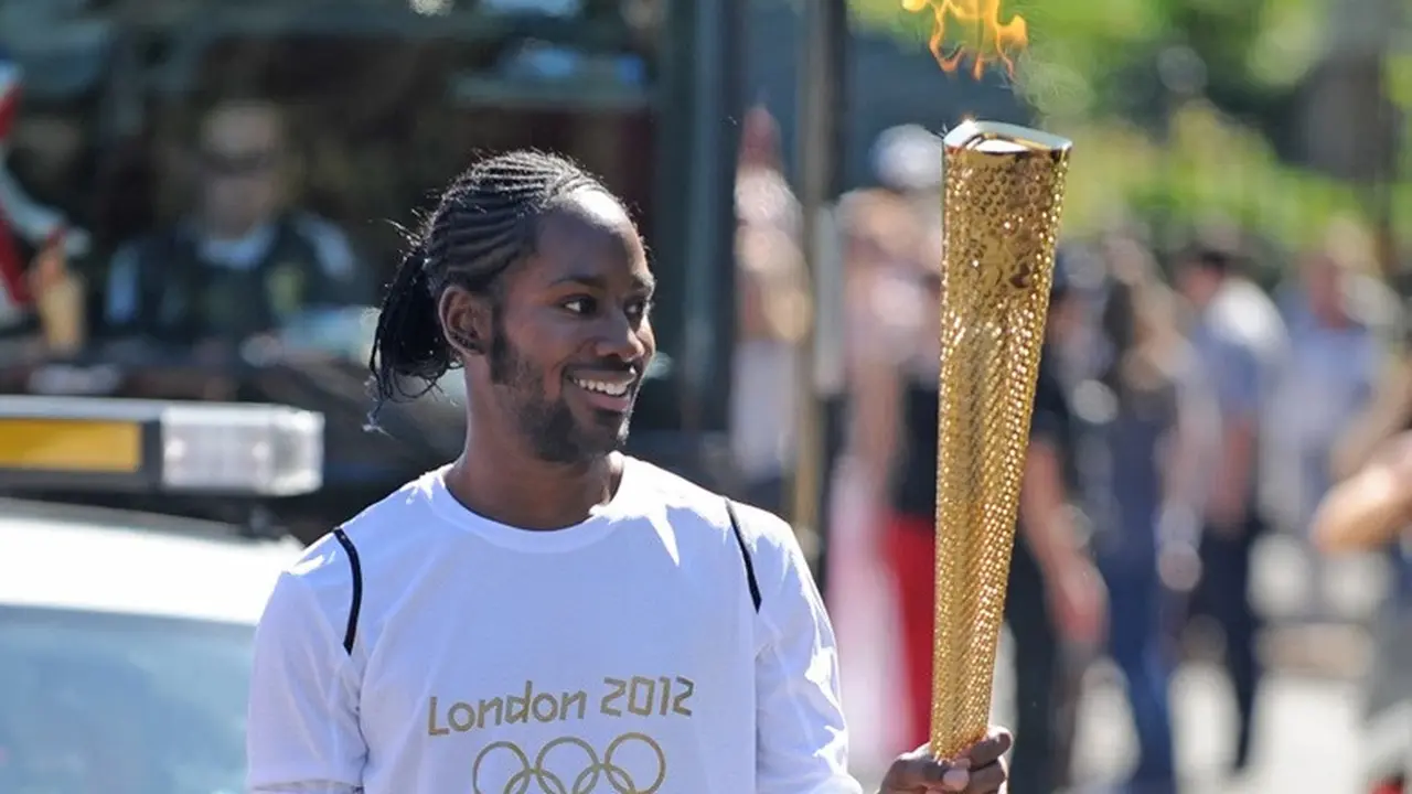 Jason Arday membawa api Olimpiade dalam estafet obor yang melintasi Sutton dan Merton, London, pada 23 Juli 2012.