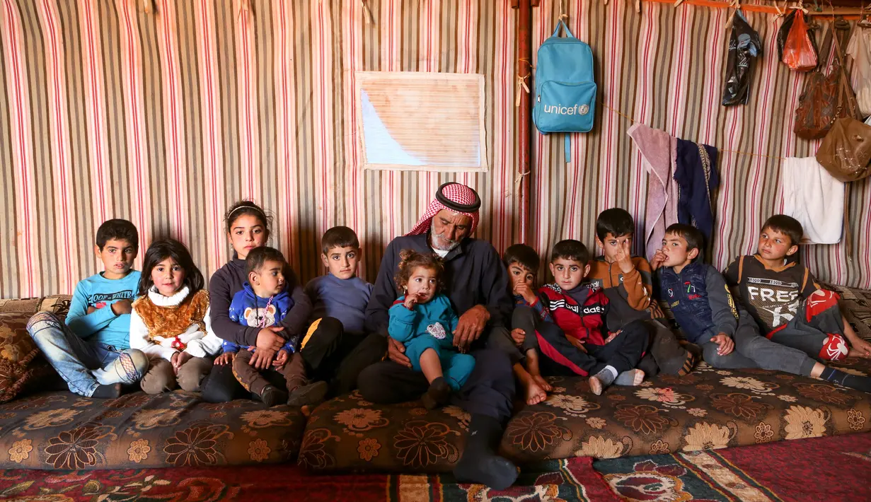 Abderrazaq Khatoun, beristirahat dengan 11 cucunya yang yatim piatu di dalam tenda di desa Harbanoush, di Idlib, Suriah pada 11 Maret 2021. Perang Suriah yang merampas 13 anak Khatoun dan salah satu istrinya, membuat kakek 83 tahun itu membesarkan 11 cucu yatim piatu sendirian. (Ahmad al-ATRASH/AFP)