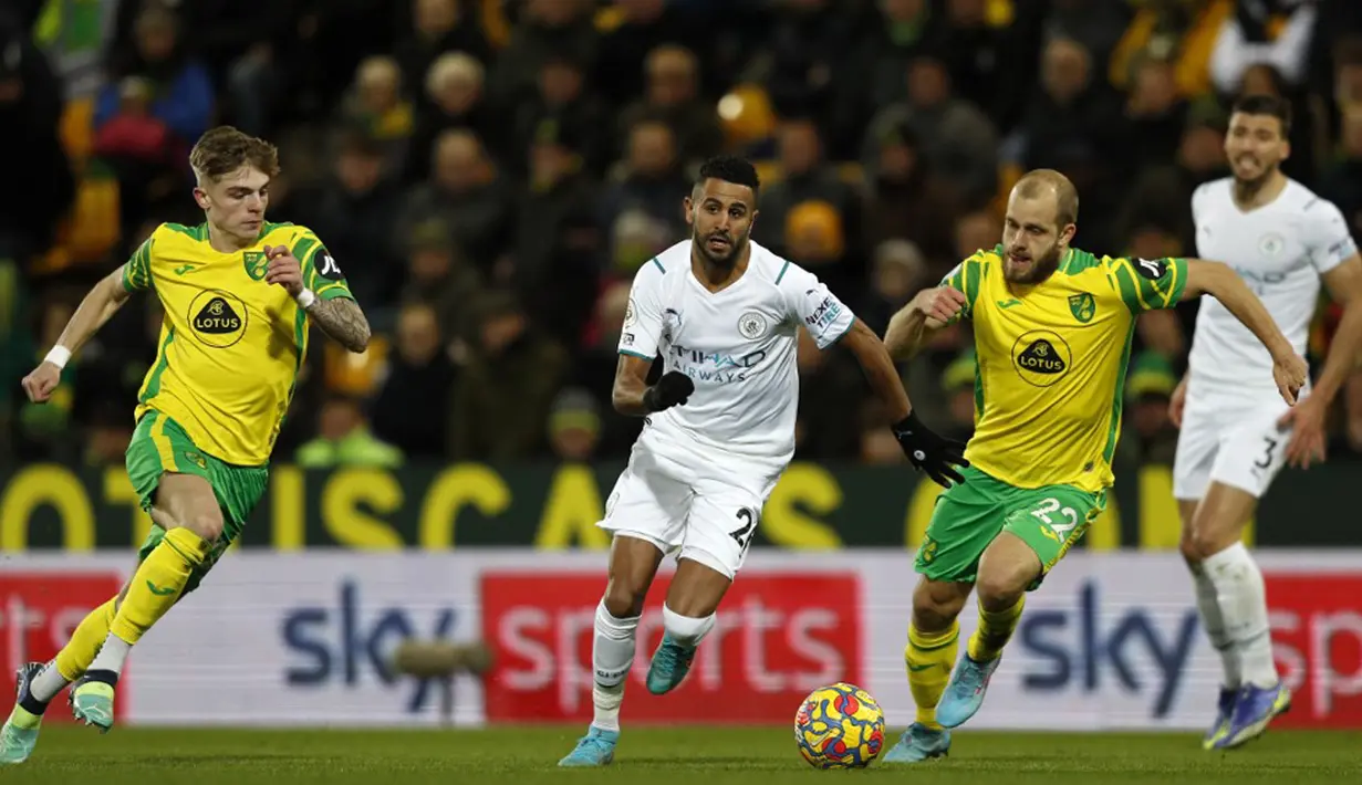 Pemain Manchester City Riyad Mahrez (tengah) berebut bola dengan pemain Norwich City Brandon Williams (kiri) dan Teemu Pukki (kedua kanan) pada pertandingan sepak bola Liga Inggris di Stadion Carrow Road, Norwich, Inggris, 12 Februari 2022. Manchester City menang 4-0. (Adrian DENNIS/AFP)
