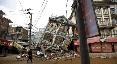 Foto yang diambil pada 1 Mei 2015 menunjukkan warga berjalan di dekat rumah yang runtuh setelah gempa 7,8 SR di Kathmandu. Setahun yang lalu, Nepal mengalami gempa terburuk dalam sejarah selama 80 tahun bencana di kawasan itu. (REUTERS/Navesh Chitrakar)