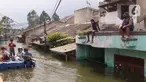 Warga melintas dengan perahu buatan saat banjir melanda perumahan Periuk Damai, Tangerang, Banten, Selasa (22/2/2021). Banjir setinggi 2,5 meter tersebut sudah terjadi selama 4 hari. (Liputan6.com/Angga Yuniar)