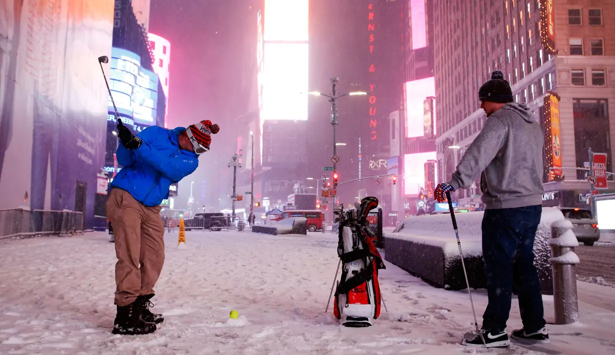 Dua pria bermain golf dengan bola tenis saat badai salju melanda kawasan Times Square, New York, (14/3). NWS menetapkan status darurat untuk negara bagian New York dan New Jersey yang terancam dilanda badai salju. (AP/Mark Lennihan)