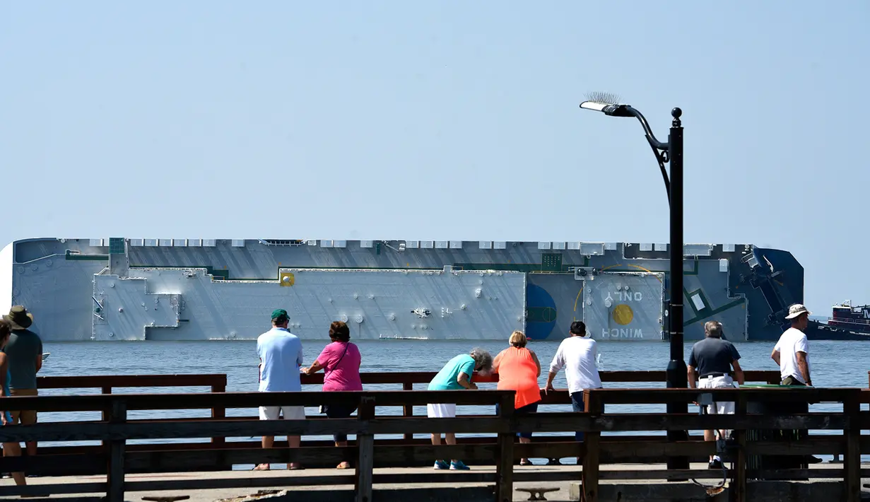 Warga melihat kapal kargo Golden Ray yang terbalik di lepas pantai negara bagian Georgia, Amerika Serikat, Minggu (8/9/2019). Kapal kargo Korea Selatan yang mengangkut 4.000 mobil itu terbalik saat menuju Timur Tengah. (Bobby Haven/The Brunswick News via AP)