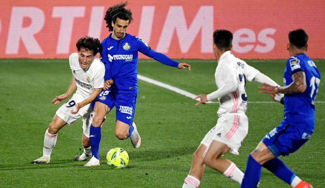 Pemain Real Madrid, Alvaro Odriozola, berebut bola dengan pemain Getafe, Marc Cucurella, pada laga Liga Spanyol di Stadion Alfonso Perez, Senin (19/4/2021). Kedua tim bermain imbang 0-0. (Photo by PIERRE-PHILIPPE MARCOU / AFP)