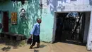 Seorang pria membawa sepatunya saat melintasi banjir di daerah perumahan dekat tepi Sungai Yamuna yang meluap di New Delhi, India, Selasa (20/8/2019). (AFP Photo/Sajjad Hussain)