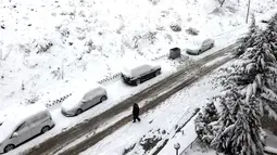 Seorang warga melewati jalan bersalju di Ankara, 23 Januari 2022.  Badai musim dingin dan hujan salju tetap berlaku di sebagian besar wilayah Turki, menyebabkan penutupan jalan antara ribuan desa dan kota di banyak daerah, beberapa hari setelah salju turun menyelimuti negara itu. (Adem ALTAN / AFP)