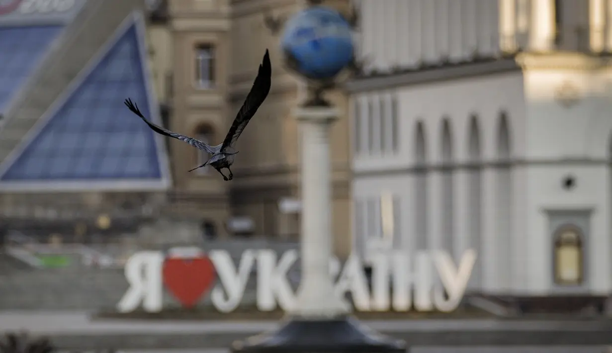 Seekor burung terbang dengan latar belakang tanda "I love Ukraina" di pusat kota Kiev, 16 Maret 2022, di tengah jam malam. Invasi Rusia ke Ukraina memasuki hari ke-21. Berbagai upaya negosiasi menuju kompromi telah dilakukan demi menuju perdamaian di antara kedua belah pihak. (AP Photo/Vadim Ghirda)