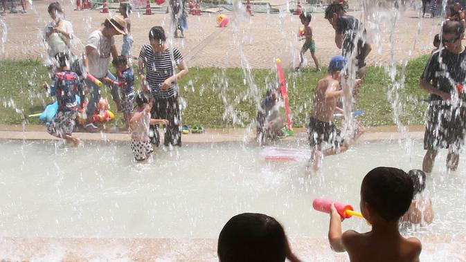 Dua orang anak bermain air di sebuah taman di Tokyo, Jepang, (16/7). Badan Meteorologi mengatakan gelombang panas terus berlanjut di wilayah metro ketika suhu naik mencapai 35 derajat Celcius (95 derajat Fahrenheit). (AP Photo/Koji Sasahara)