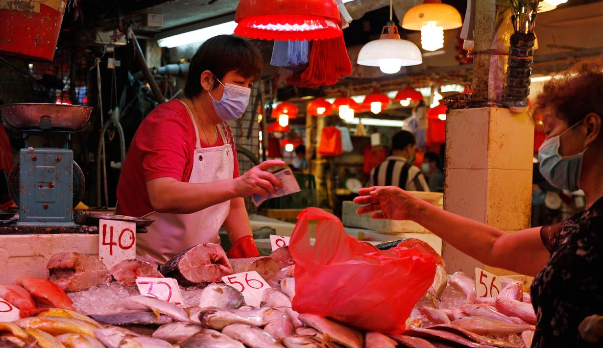 Seorang penjual dan pelanggan memakai masker di pasar lokal di Hong Kong, Rabu (22/7/2020). Hong Kong telah mewajibkan penggunaan masker di semua area publik tertutup termasuk mal dan pasar seiring penambahan kasus baru harian Covid-19. (AP Photo/Kin Cheung)