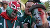 Suporter Meksiko menggunakan topeng saat merayakan kemenangan timnya atas Jerman pada laga grup F Piala Dunia 2018 di Luzhniki Stadium, Moskow, (17/6/2018). Meksiko menang 1-0. (AP/Alexander Zemlianichenko)