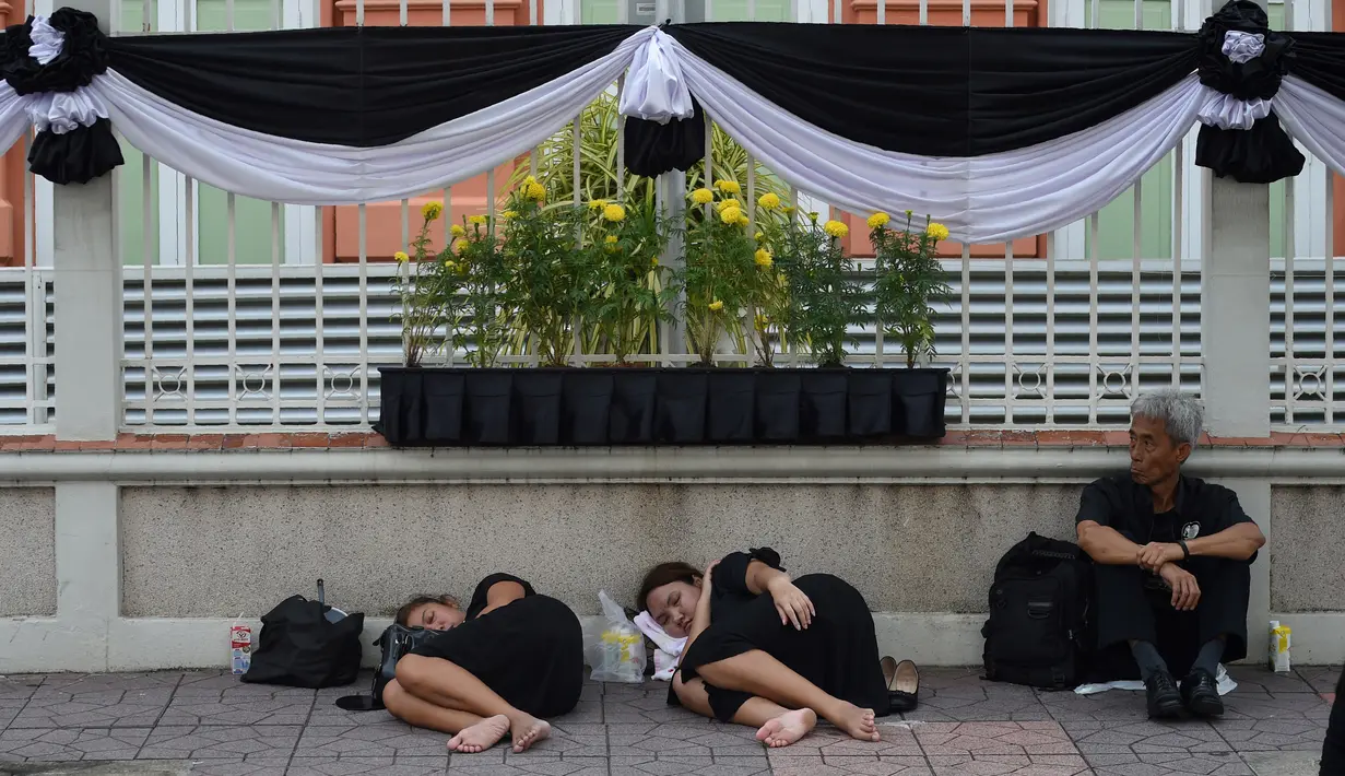 Dua orang wanita tidur saat menunggu pemakaman mendiang Raja Thailand Bhumibol Adulyadej di Bangkok (25/10). Upacara pemakaman Raja Bhumibol Adulyadej ini akan berlangsung selama lima hari. (AFP Photo/Roberto Schmidt)