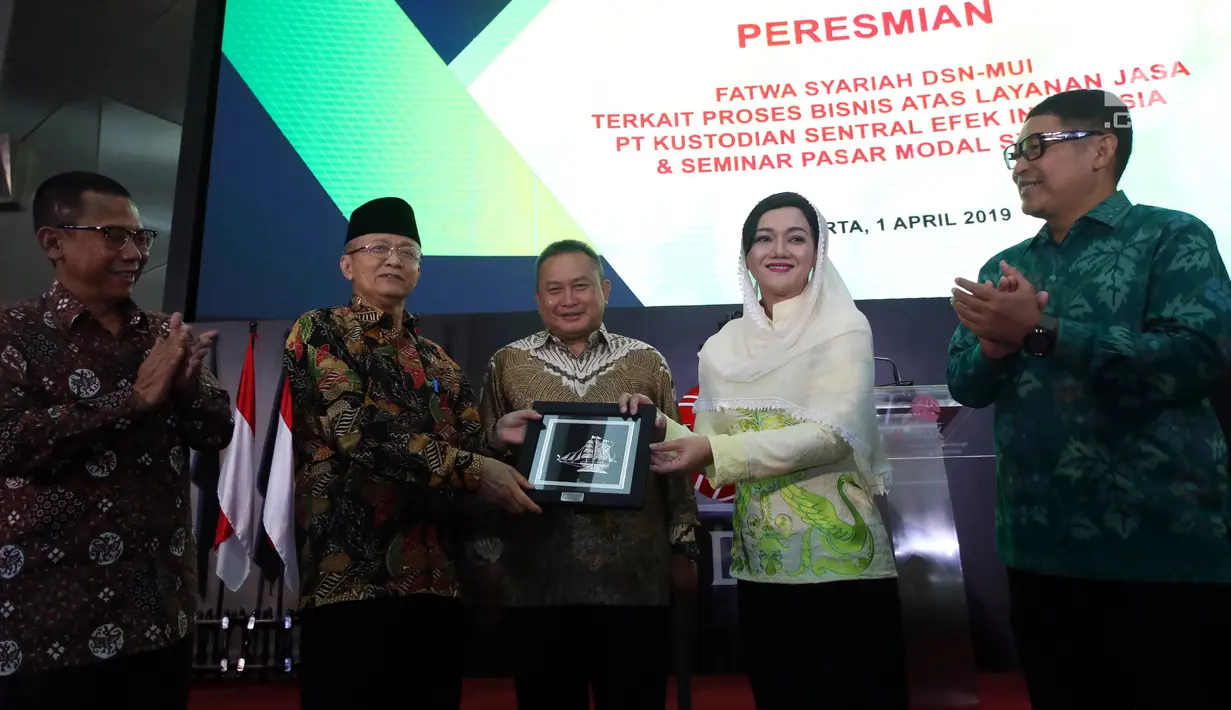 Sekretaris DSN-MUI, Anwar Abbas (kedua kiri) dan Direktur Utama PT Kustodian Sentral Efek Indonesia (KSEI), Friderica Widyasari Dewi (kedua kanan) saat penyerahan fatwa syariah terkait proses Bisnis Atas Layanan Jasa di Gedung Bursa Efek Indonesia, Jakarta, Senin (1/4). (Liputan6.com/Johan Tallo)