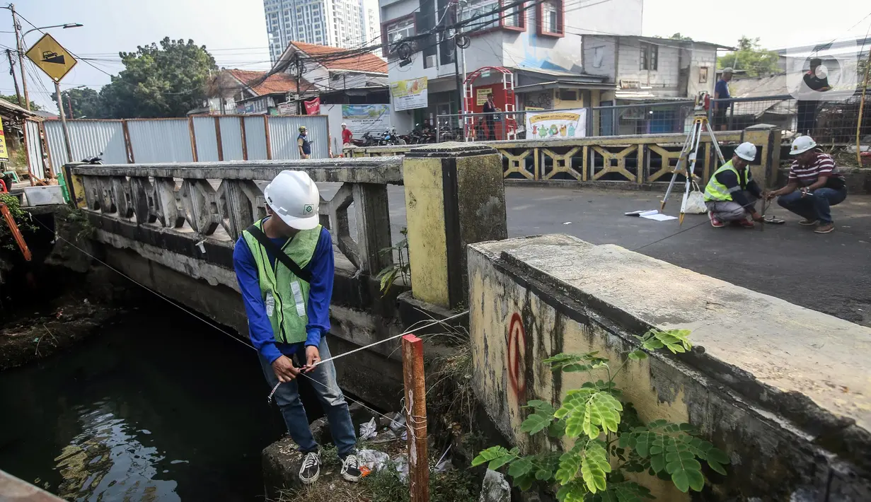 Pekerja melakukan pengukuran saat menyelesaikan proyek revitalisasi Jembatan Cibubur, Jakarta, Selasa (2/8/2022). Revitalisasi dilakukan untuk mengantisipasi risiko banjir akibat rendahnya muka jembatan serta risiko kecelakaan akibat tidak adanya trotoar. (Liputan6.com/Faizal Fanani)