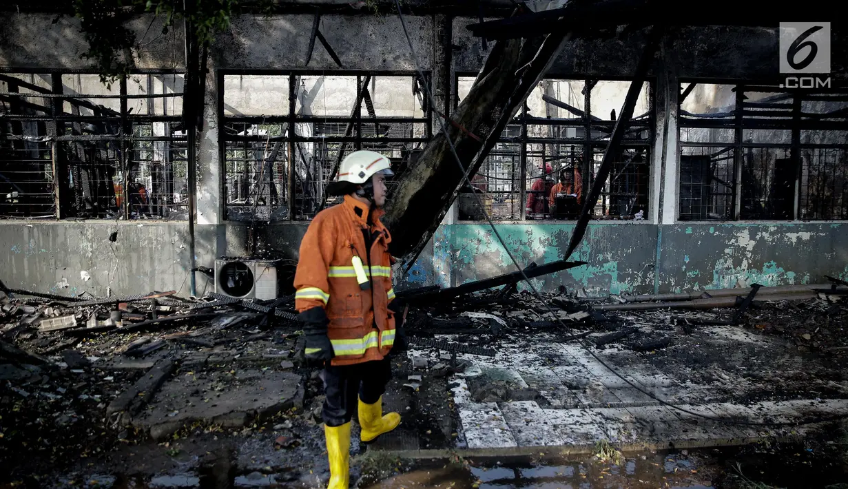 Petugas pemadam kebakaran mengamati sisa Stasiun Klender, Jakarta Timur yang terbakar, Jumat (19/5). Kebakaran yang terjadi sekitar 07.30 WIB di Stasiun Klender ini melalap kantor kepala stasiun hingga loket tiket. (Liputan6.com/Faizal Fanani)
