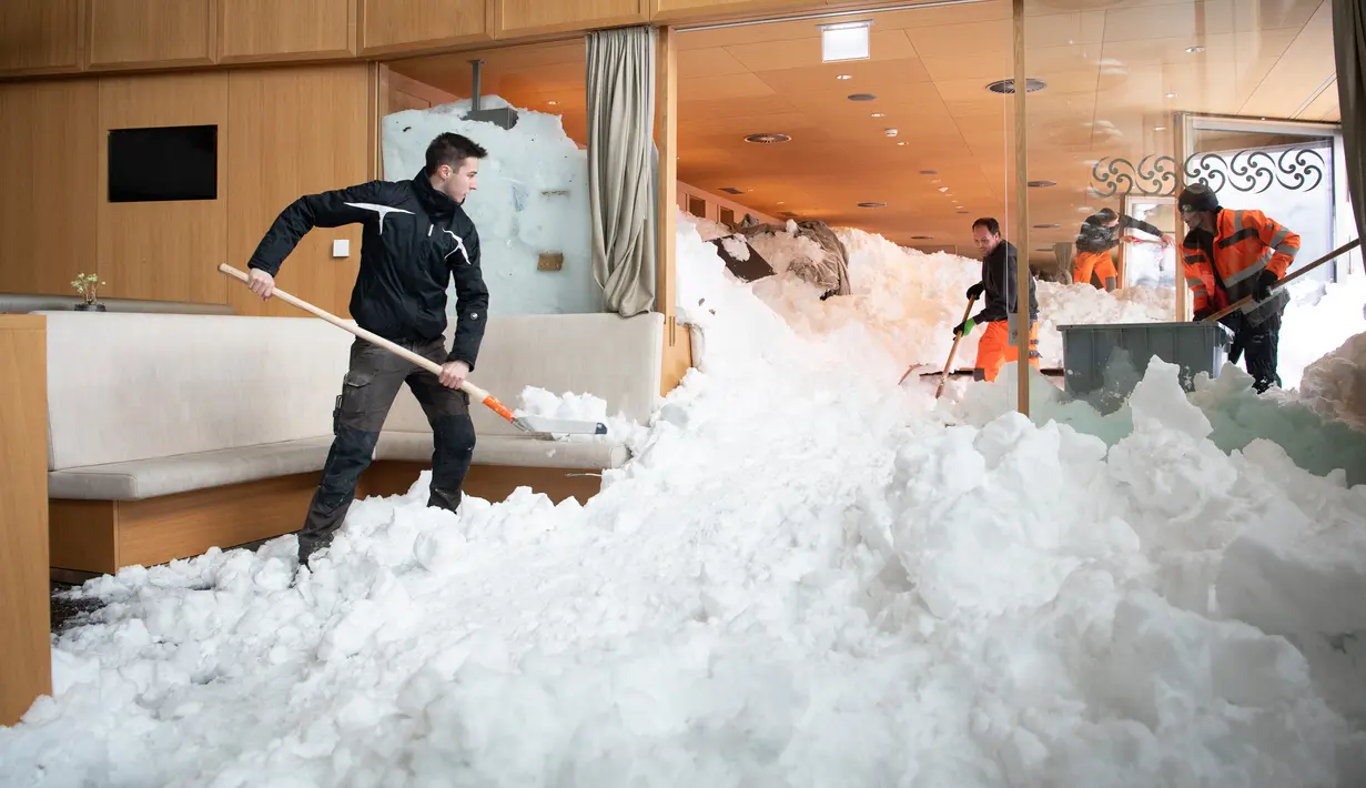 Petugas membersihkan longsoran salju yang masuk ke dalam Hotel Saentis di Schwaegalp, Swiss, Jumat (11/1). Polisi mengatakan tiga orang terluka dalam insiden tersebut. (Gian Ehrenzeller/Keystone via AP)