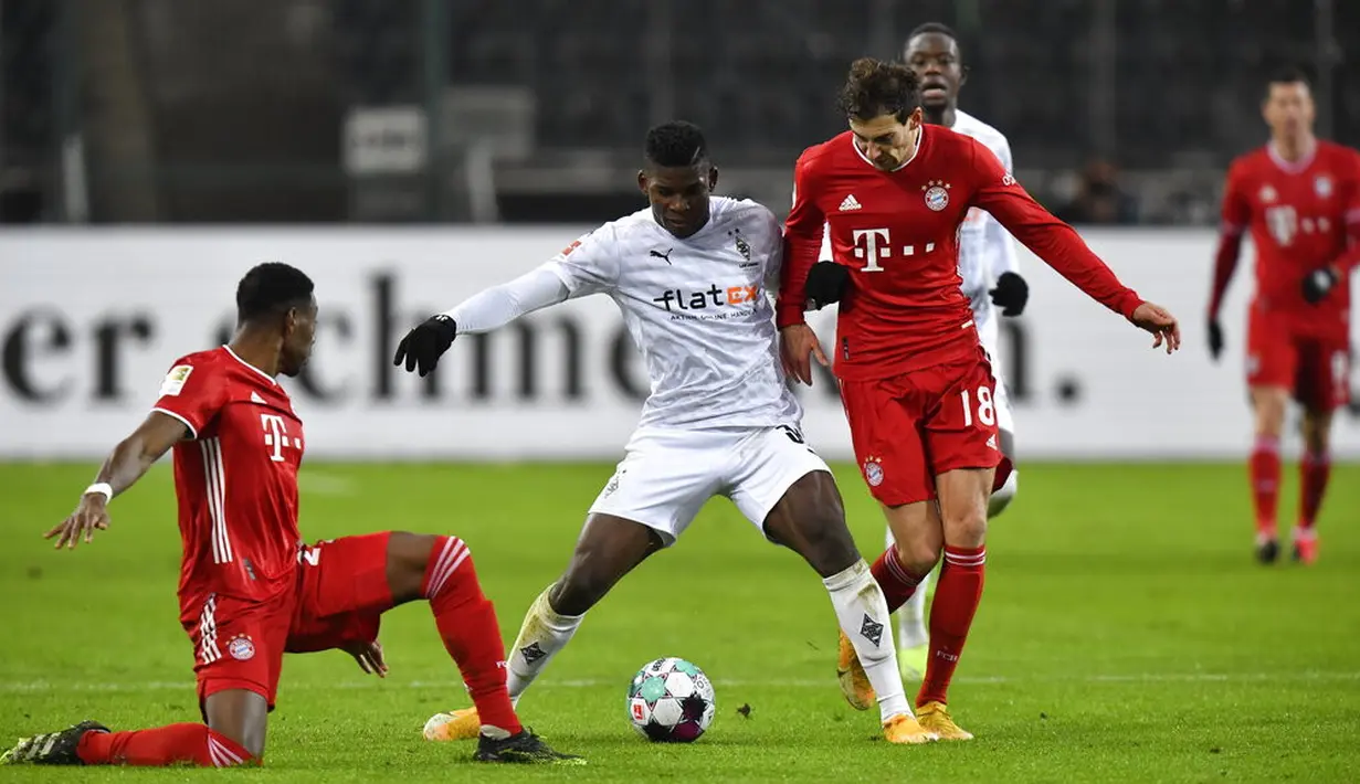 Pemain Borussia Moenchengladbach Breel Embolo (tengah) berebut bola dengan pemain Bayern Munchen Leon Goretzka (kanan) pada pertandingan Bundesliga di Borussia Park, Moenchengladbach, Jerman, Jumat (8/1/2021). Bayern Munchen kalah 2-3. (AP Photo/Martin Meissner, Pool)