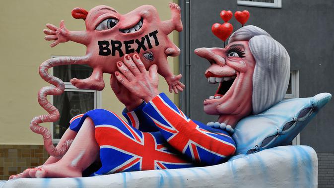 Kereta karnaval membawa karikatur yang menggambarkan Perdana Menteri Inggris, Theresa May melahirkan bayi Brexit-nya dalam parade karnaval Rose Monday di Duesseldorf, Jerman, Senin (12/2). (AP Photo/Martin Meissner)