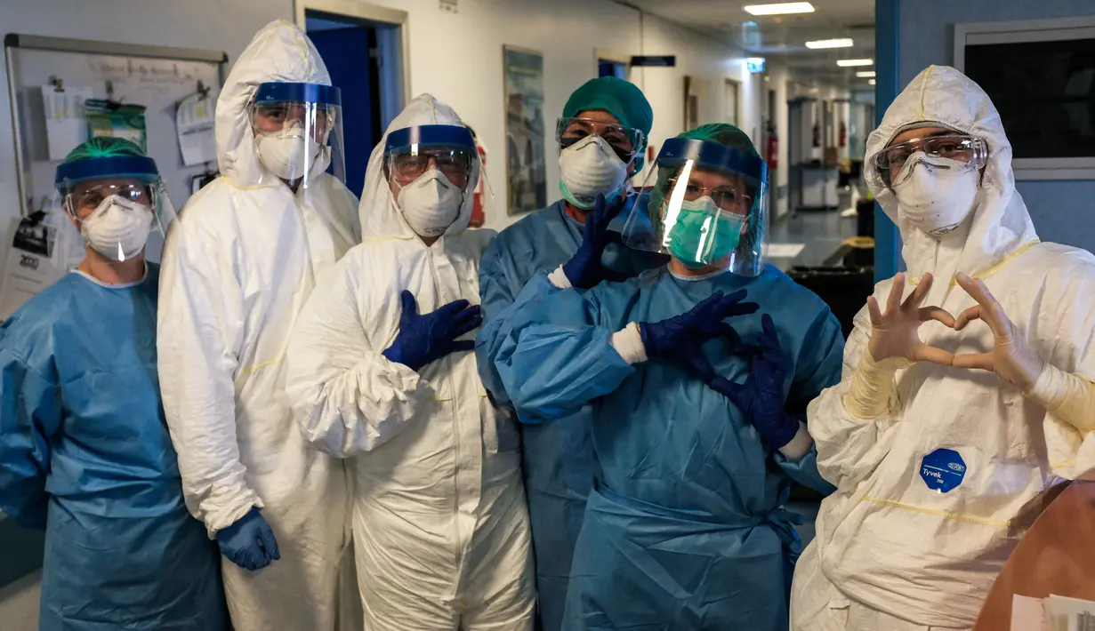 Sekelompok perawat dengan alat pelindung diri berpose sebelum shift malam mereka di rumah sakit Cremona, tenggara Milan, Lombardy pada 13 Maret 2020. Para pekerja kesehatan Italia kelelahan setelah selama bermingu-minggu berada di garda terdepan memerangi pandemi virus corona. (Paolo MIRANDA/AFP)
