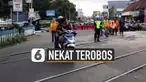 Lelaki berambut gondrong nampak tak menghiraukan himbauan dari petugas dan relawan perlintasan yang berjaga.