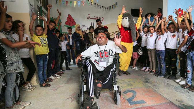 Nihad Jarboa (37) dikelilingi oleh anak-anak dan relawan, salah satunya mengenakan kostum yang dibuat oleh dia dan istrinya Zeinab, di sebuah pusat anak-anak dengan penyakit kronis di kamp pengungsi Rafah di Jalur Gaza selatan, pada 21 Juli 2020. (AFP Photo/Said Khatib)