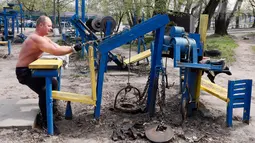 Seorang pria berlatih menarik beban di outdoor gym atau pusat kebugaran terbuka di tepi Sungai Dnipro, Kiev, Ukraina, Kamis (18/4). Pusat kebugaran ini memanfaatkan besi tua bekas kendaraan sebagai alat fitness. (AP Photo/Efrem Lukatsky)