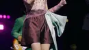 Dipadu celana pendek satin merah marun dan selempang satin hijau mint yang diikat di pinggang.  Menciptakan siluet dramatis dan playful sekaligus