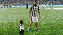 Carlos Tevez (kanan) bermain bersama anaknya di tengah perayaan gelar juara Serie A 2014-15 di Juventus Arena, Italia, (23/5/2015). Ini merupakan Gelar ke-31 Juventus di Serie A. (Reuters/Giorgio Perottino)
