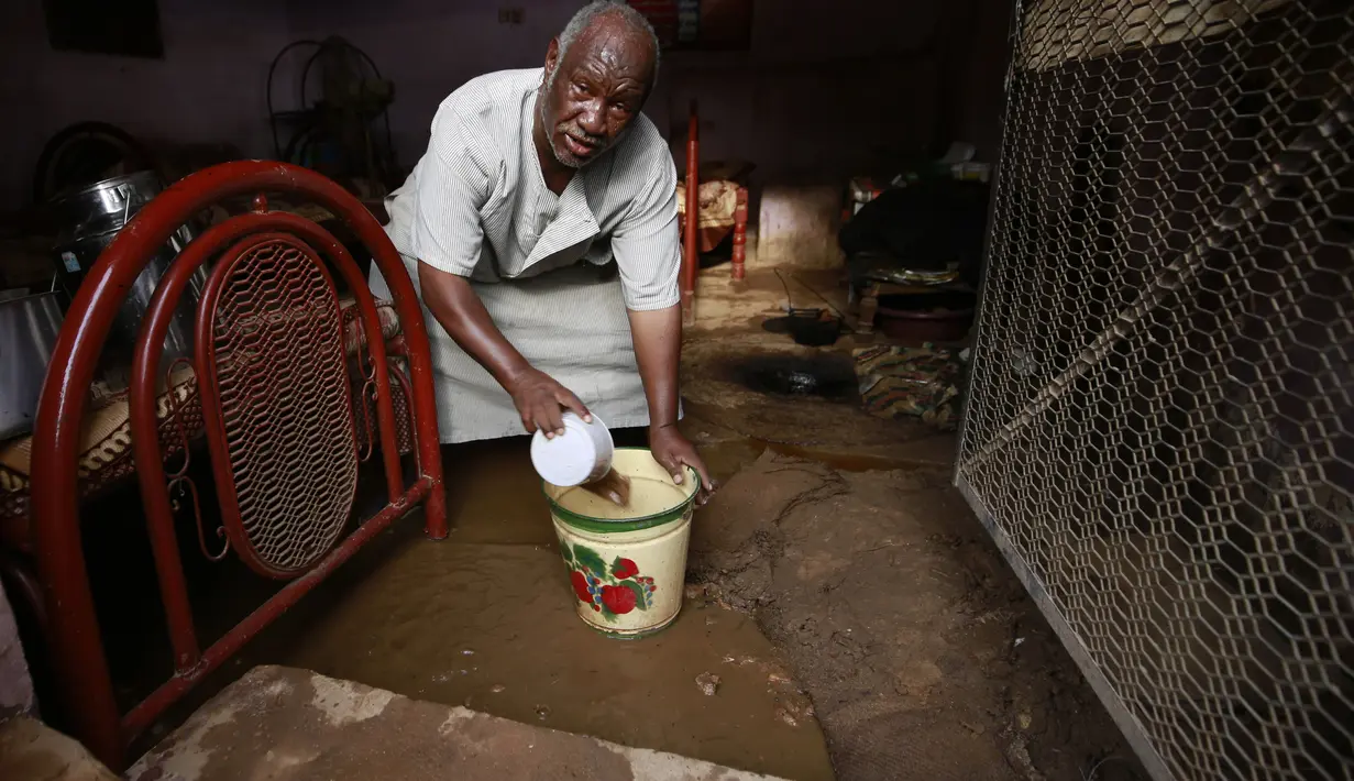 Seorang pria Sudan mengeluarkan air dari rumahnya di daerah banjir alqamayir di kota kembar ibu kota Omdurman (26/8/2020). (AFP Photo/Ashraf Shazly)