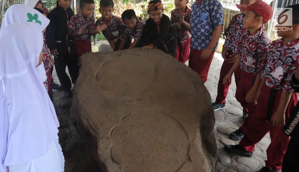 Murid SD melihat prasasti telapak kaki gajah di Prasasti Kebun Kopi, Ciaruteun Ilir, Bogor, Jawa Barat, Rabu (15/8). Prasasti ini peninggalan budaya Kerajaan Tarumanegara yang berdiri pada abad 4 hingga 7 masehi di Pasundan. (Merdeka.com/Arie Basuki)