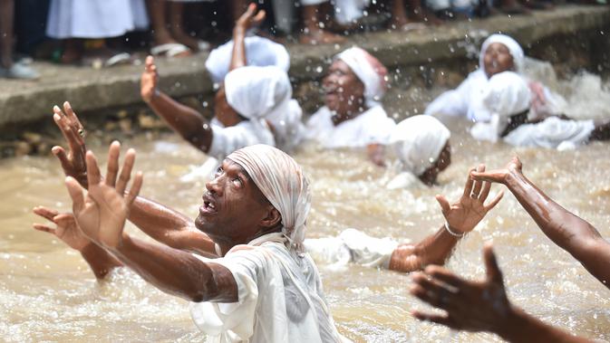 Pengikut Voodoo Haiti mandi di kolam suci selama upacara voodoo di Souvenance, Haiti (4/1). Sejumlah ritual digelar para pengikuti Voodoo Haiti ini selam akhir pekan perayaan Paskah. (AFP/Hector Retamal)