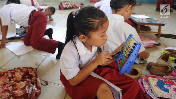 Seorang murid kelas II melakukan kegiatan belajar di lantai kelas SDN Kertajaya 2, Rumpin, Bogor, Senin (3/9). Tidak tersedianya meja dan kursi di tiga ruang kelas menyebabkan mereka belajar di lantai selama lebih dari 3 tahun. (Merdeka.com/Arie Basuki)