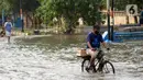 Warga menggunakan sepeda melintasi genangan banjir rob yang menggenangi kawasan Pelabuhan Nizam Zachman, Muara Baru,  Jakarta, Jumat (5/6/2020). Banjir rob di Pelabuhan Muara Baru tersebut terjadi akibat cuaca ekstrem serta pasang air laut. (Liputan6.com/Helmi Fithriansyah)