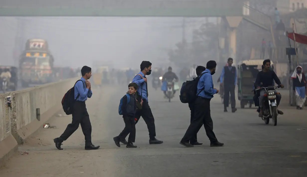 Siswa menyeberang jalan dalam perjalanan ke sekolah pada pagi yang berkabut di Lahore, Pakistan, Selasa (30/11/2021). Lahore secara konsisten menempati peringkat sebagai salah satu kota terburuk di dunia untuk polusi udara. (AP Photo/K.M. Chaudary)