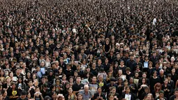 Puluhan ribu pelayat berpakaian hitam berkumpul di luar Grand Palace sambil menyanyikan rekaman lagu kerajaan, di Bangkok, Thailand, (22/10). Sebagian mereka membawa foto dan poster untuk menghormati raja mereka. (REUTERS/Jorge Silva)