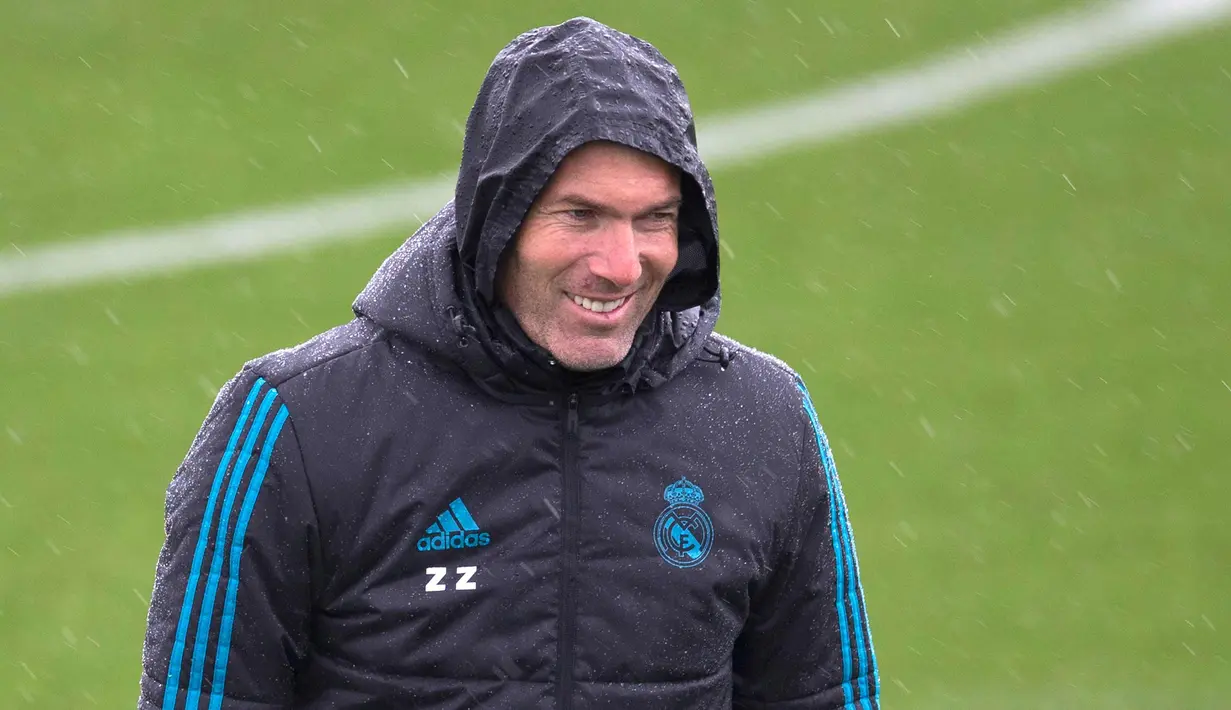 Pelatih Real Madrid, Zinedine Zidane tersenyum saat menyaksikan para pemainnya berlatih di Madrid, Spanyol (10/4). Madrid akan bertanding melawan Juventus pada leg kedua perempat final Liga Champions di Stadion Bernabeu. (AP Photo/Paul White)