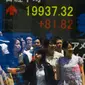 Sejumlah orang tercermin dalam papan yang menampilkan indeks saham di Tokyo, Jepang, Jumat, (10/7/ 2015). Harga saham Nikkei mengalami perubahan mengikuti gejolak pasar Tiongkok. (REUTERS/Thomas Peter)