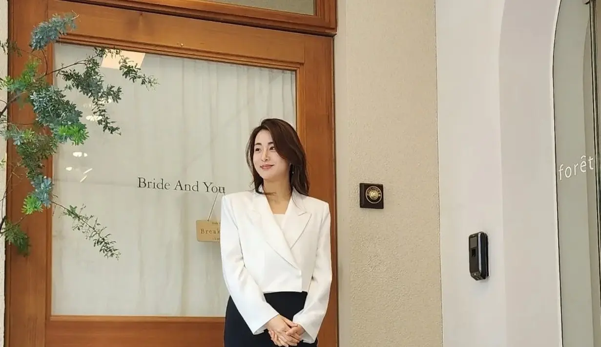 Potret memesona Kang Sora dalam balutan work-wear. Ia tampil bak seorang CEO dengan cropped blazer putih dan celana panjang hitam. [Foto: Instagram/reveramess_]