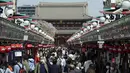 Orang-orang yang mengenakan masker pelindung untuk membantu mengekang penyebaran virus corona melalui arena perbelanjaan di distrik Asakusa di Tokyo, Rabu (31/3/2021).  Ibukota Jepang mengonfirmasi lebih dari 410 kasus virus corona baru pada hari Rabu. (AP Photo/Eugene Hoshiko)