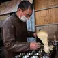 Seorang pedagang menuangkan adonan ke dalam cetakan kue di pasar di Beijing (20/11). (AFP Photo/Nicolas Asfouri)