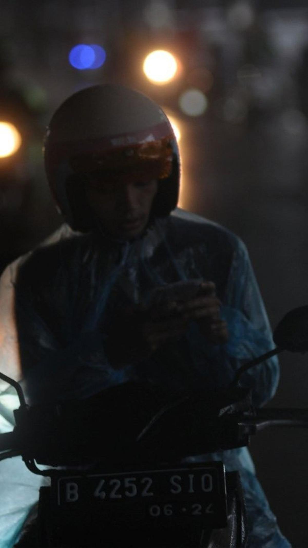 Seorang pengendara sepeda motor berteduh di kolong Halte Panglima Polim saat hujan dan angin kencang melanda Jakarta, Selasa (9/4/2024). Foto: merdeka.com / Imam Buhori