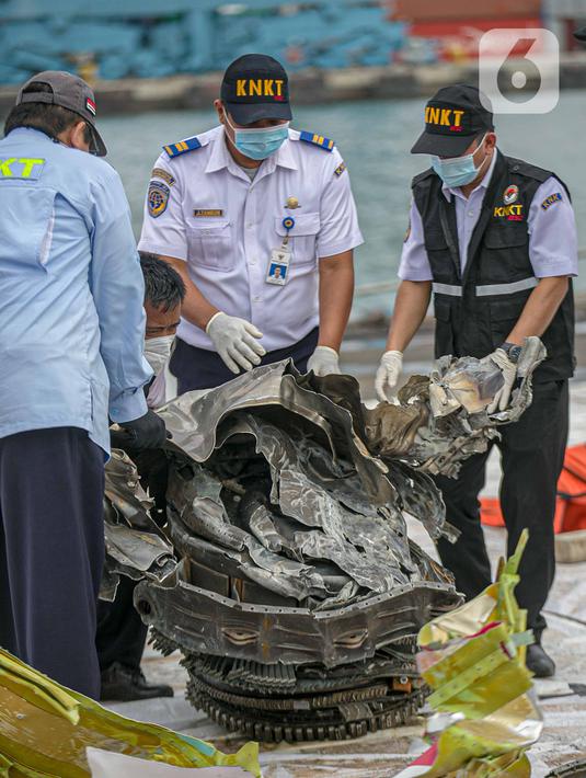 Petugas KNKT memeriksa bagian turbin pesawat Sriwijaya Air dihari kelima yang jatuh di perairan Pulau Seribu, di Dermaga JICT, Jakarta,  Rabu (13/1/2021). Pengangkatan mesin turbin pesawat Sriwijaya Air SJ 182 itu menggunakan crane milik KRI Cucut 866. (Liputan6.com/Faizal Fanani)