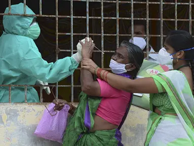 Seorang wanita (tengah) bereaksi ketika petugas kesehatan mencoba mengumpulkan sampel usapnya untuk menguji virus corona Covid-19 di daerah kumuh di Hyderabad (23/9/2020). (AFP/Noah Seelam)