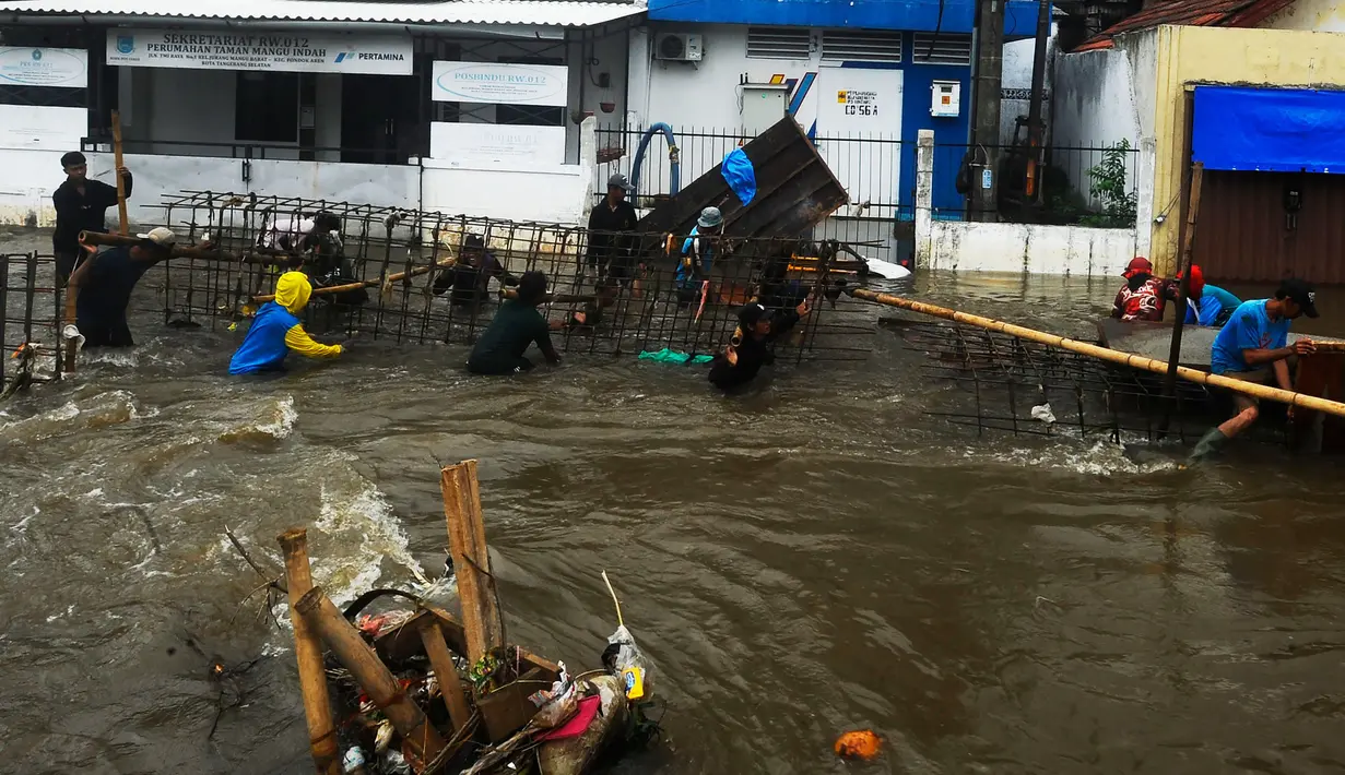 Pekerja membuat penahan tanggul jebol saat banjir merendam Perumahan Taman Mangu Indah, Jurangmangu Barat, Pondok Aren, Tangerang Selatan, Banten, Selasa (12/11/2024). (merdeka.com/Arie Basuki)