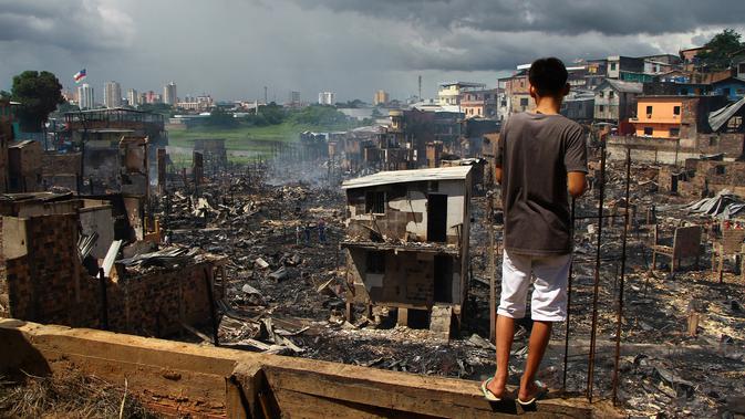 Seorang pria melihat sisa-sisa rumah yang hangus di lingkungan Educandos di Manaus, Brasil (17/12). Kebakaran diduga disebabkan oleh ledakan panci presto yang menghanguskan ratusan rumah warga. (AP Photo/Edmar Barros)