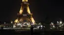 Terima Kasih Eiffel untuk Tenaga Medis Covid-19: Awak media berdiri di depan Menara Eiffel dengan tulisan 'Merci" (terima kasih) di Paris, Jumat (27/3/2020). Menara Eiffel menampilkan pesan dukungan dan terima kasih kepada tenaga kesehatan di Prancis yang memerangi COVID-19. (AP/Thibault Camus)