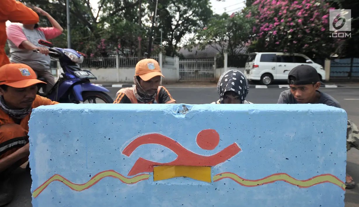 Pekerja dari PPSU Kelurahan Pegangsaan saat membuat lambang cabang olahraga di pembatas Jalan Penataran atau Simpang Tugu Proklamasi, Jakarta, Rabu (25/7). (Merdeka.com/Iqbal S. Nugroho)